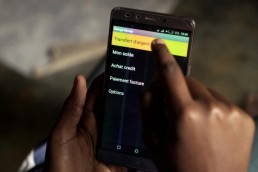 Katy shows how she uses Mobile Money on her phone in Ivory Coast