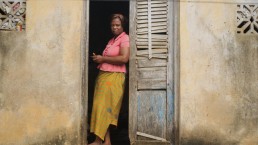 Elyse uses mobile money on her phone at her home in Ivory Coast