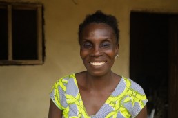 Alice smiles outside her home as she explains how Mobile Money lets her safely store her income in Ivory Coast
