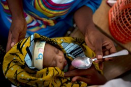 A baby is fed cough medicine after displaying measles symptoms in Tanzania