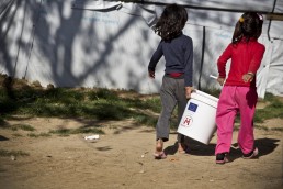 Young Syrian refugee girls carry a bucket in Lebanon