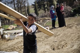 A young Syrian refugee boy carries a plank of wood in Lebanon