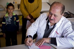 A doctor writes a prescription for a Syrian refugee boy in Lebanon