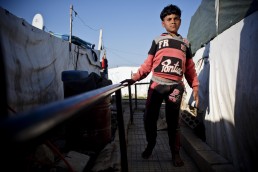 A disabled Syrian refugee boy walks with the help of a rail in Lebanon
